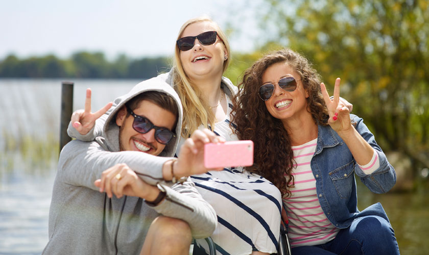 Ett gäng ungdomar ler och tar selfie vid en sjö