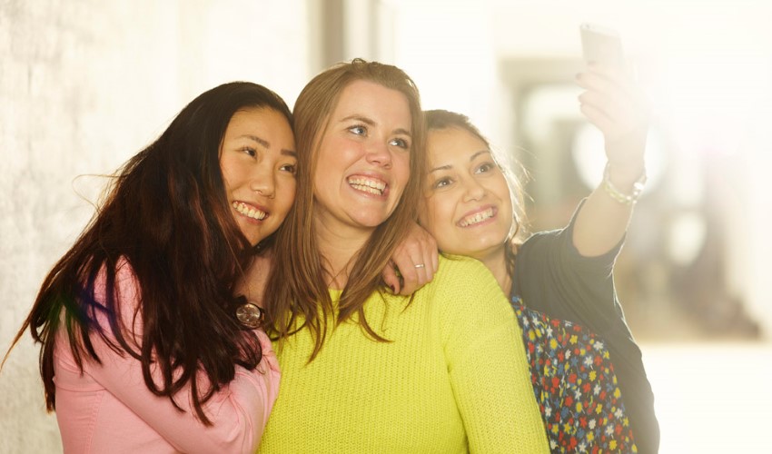 Tre kvinnor tar en selfie.